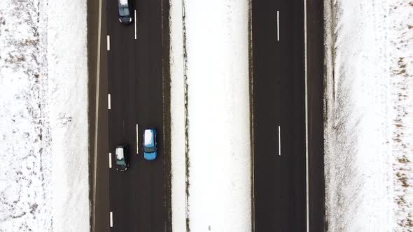 Four-lane highway with driving vehicles in winter season, aerial top down view