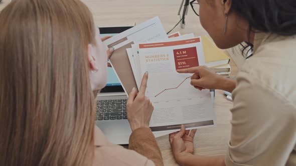 Two Women Analyzing Financial Document in Office