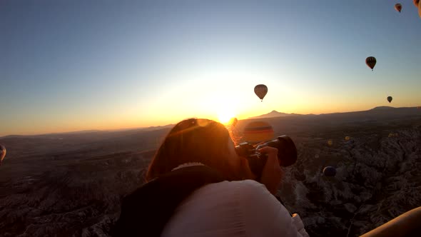 Girl taking pictures in hot air balloon at sunrise, Cappadocia, Turkey