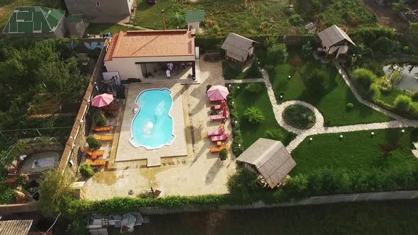 Flyover View of Topless Male Jumping Into Pool While Another Two Men Walking Near in White Bathrobes