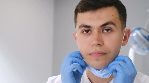 The Surgeon Wears a Protective Mask and Looks Into the Camera Lens