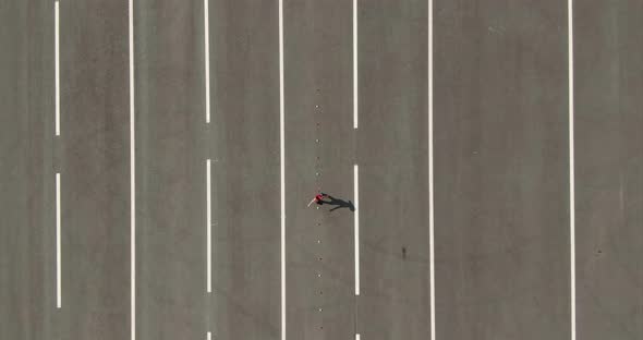 Aerial View, a Girl Athlete Trains on the Square. Girl on Roller Skates Goes Around the Cones. View