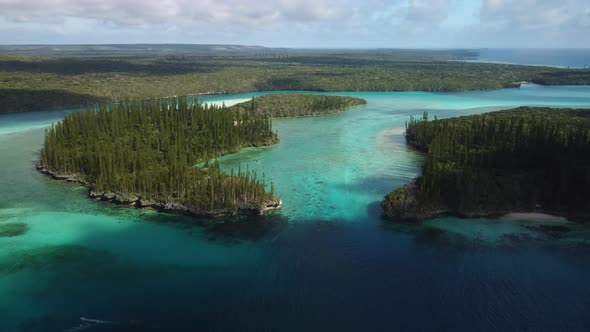 Amazing aerial parallax view of the Isle of Pines and Oro's Bay as the forest stretches to the horiz