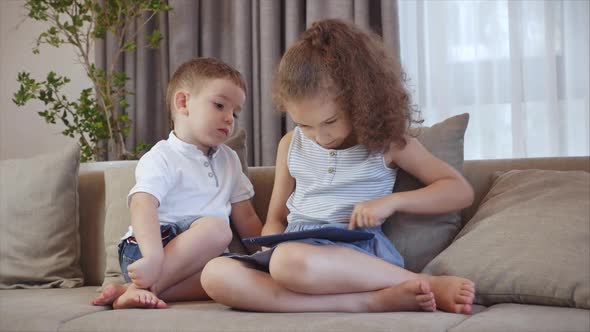 Cute Family and Daughter,sister-in-law a Nanny with Little Brother,looking at the Screen of a Tablet