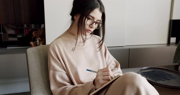 Attractive Woman Freelance Writer is Writing His Article on a Notebook