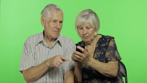 Senior Aged Man and Woman Sitting Together and Working on Smartphone. Chroma Key