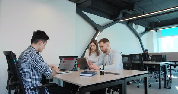 Three Adults are Working on Laptops in a Coworking Space