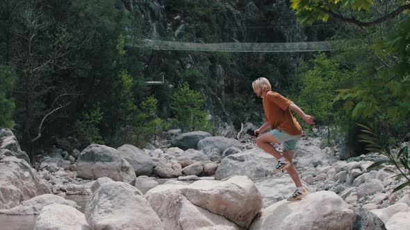 A Young Man Climbs Up the Rocks and Searches for the Network From the Phone