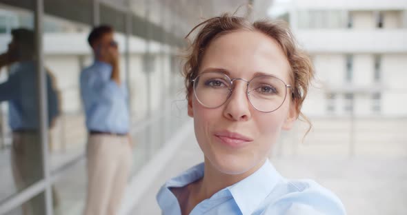 Young Businesswoman with Brace Having Video Call Standing Outside Office Building