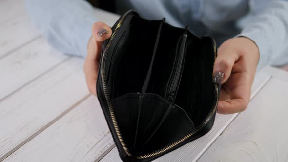 Closeup of a Young Woman Holding an Empty Wallet on a Light Wooden Background