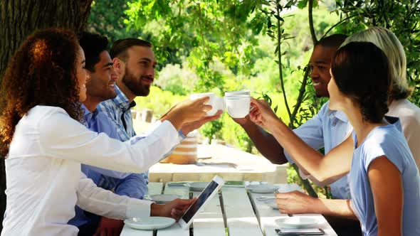 Group of friends toasting coffee cups at outdoor cafe