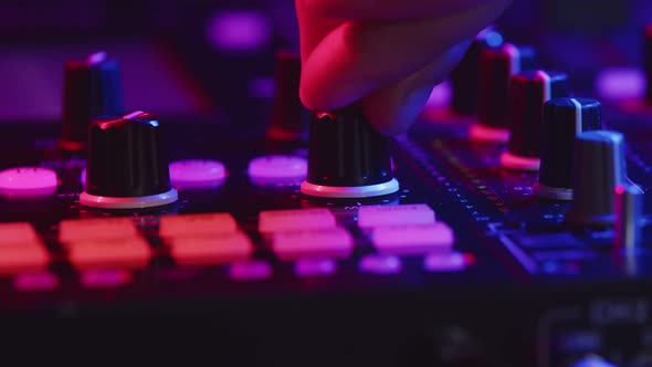 Professional DJ is Adjusting Fader on Digital Music Console in Pink Neon Light in Nightclub