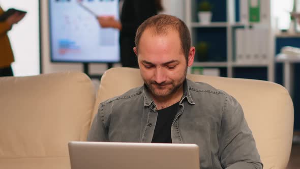 Manager Sitting on Couch in Front of Camera Smiling