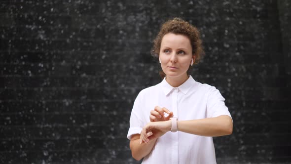 Young Stylish Woman Listening Music In Wireless Earphones Using Smartwatch