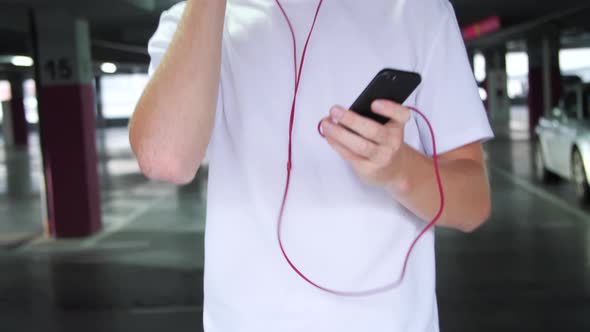 Young Man In Earphones Listening Music And Using Phone