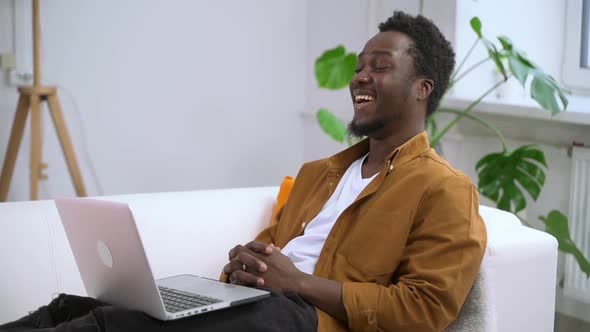 Man Laughs While Sitting at Computer Laptop and Talking with Friends Via Video Call at Home Spbas