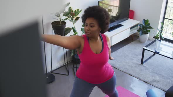 African american female plus size standing on exercise mat working out