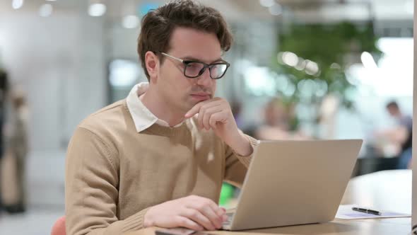 Man Thinking While Working on Laptop in Office