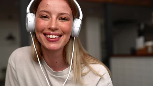 Laughing blonde woman in headphones looking at camera