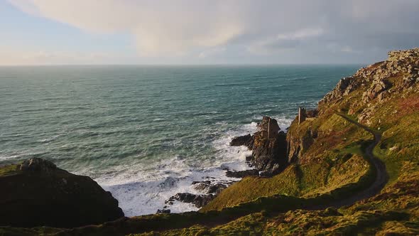 Botallack Tin Mines on seashore cliffs in Cornwall, England, with ocean landscape, on sunny evening