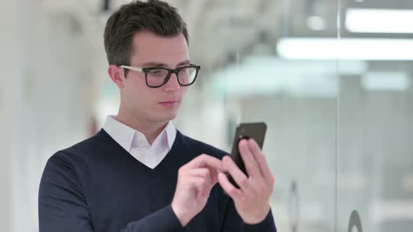 Excited Young Businessman Celebrating Success on Smartphone