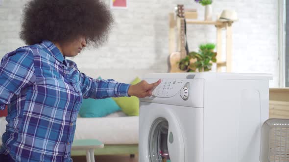 Tired African American Young Woman Housewife Busy with Homework Uses Washing Machine