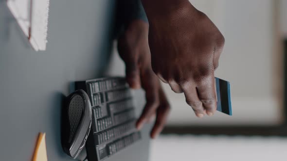 Vertical Video Close Up of African American Man Hands Typing Credit Card Info on Computer Keyborad