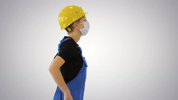 Female Construction Worker in Overalls and in Medical Mask Walking on Gradient Background. alt
