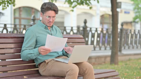 Man having Loss while Reading Documents with Laptop