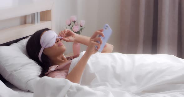 Woman Lying on the Bed Watches the Time on Her Cell Phone and Continues to Sleep