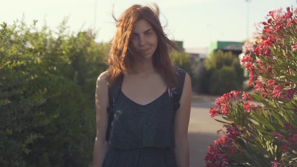 Young Attractive Redhaired Woman Enjoying Beautiful Pink Frangipani Flowers at Sunset in France Park