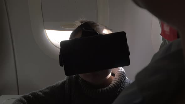 In plane sits a little boy with virtual reality glasses