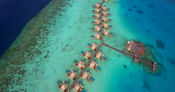 Aerial drone view of scenic tropical island and resort hotel with overwater bungalows in Maldives.