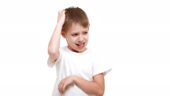 Young Thoughtful Elementaryschool Aged Caucasian Boy Scratching Head and Standing on White