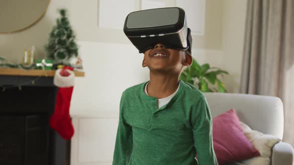 Animation of happy african american boy wearing vr headset and having fun at christmas time