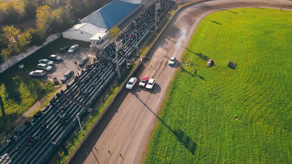 Aerial View Races on the Racetrack. Cars Driving in a Circle Drifting Around Corners Compete