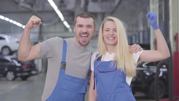 Young Caucasian Man and Woman Showing Strength Gesture, Looking at Camera and Smiling, Professional