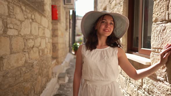 Front View Smiling Young Beautiful Woman Standing in Narrow Street on Cyprus Admiring Walls in