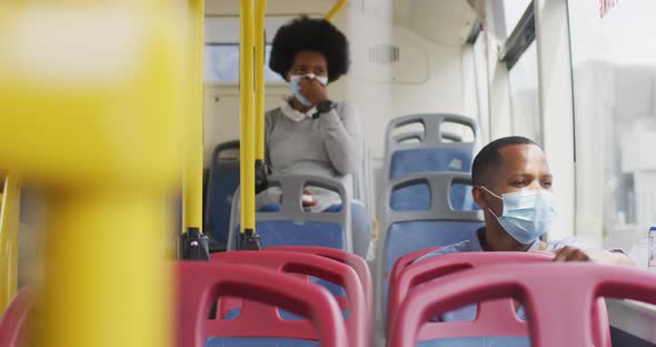 African american man and woman with face masks sitting in bus