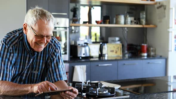 Senior man using mobile phone in kitchen 4k