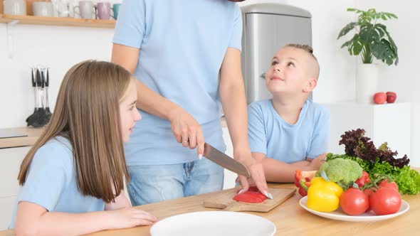 Mom and Children Cut Fresh Vegetables in the Kitchen a Happy Family Prepares Food Together