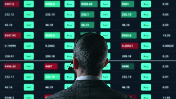 Trader is Working with Multiple Computer Screens Full of Charts and Data Analysis and Stock Broker