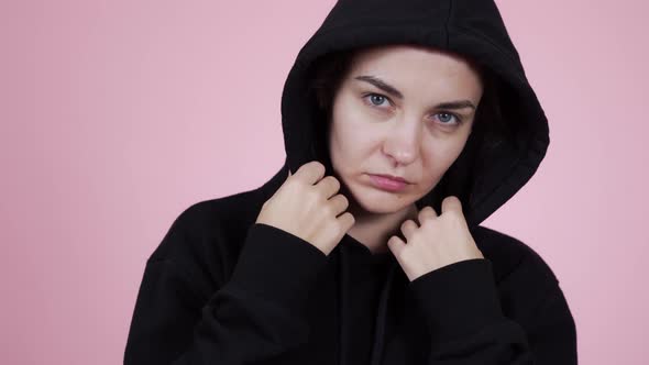 Close-up of a Sad Young Woman in a Black Hoodie Looks Into the Mirror 