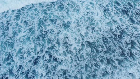 Aerial drone view of ocean waves washing over a beach