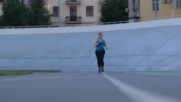 Overweight Woman Runner Training on Stadium Track