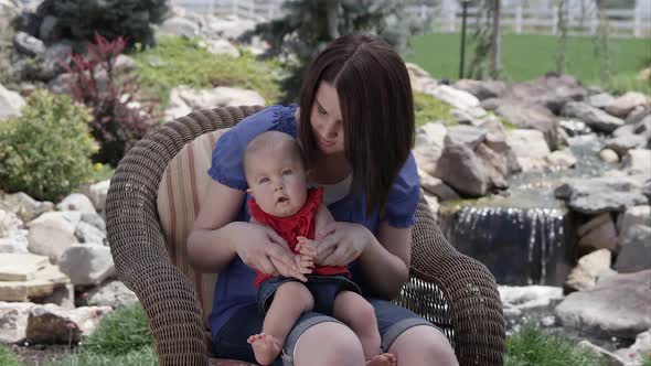 Mother with baby outside sitting in a chair.