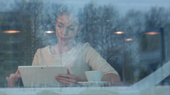 Happy Young Woman Using Digital Tablet in a Coffee Shop