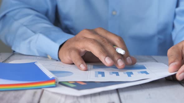 Man Hand with Pen Analyzing Bar Chart on Paper 