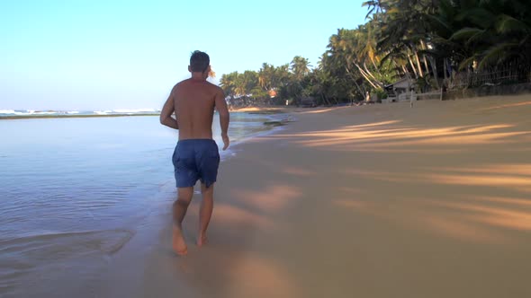 Muscular Gymnast Runs Along Yellow Sand Slow Backside