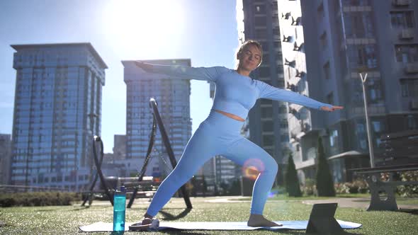 Fit Woman Doing Yoga Exercise Among City Buildings